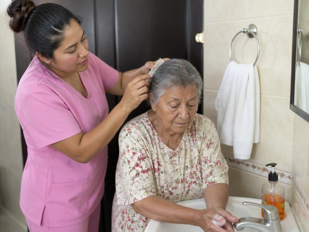 Cuidadora auxiliando idosa nos cuidados de higiene